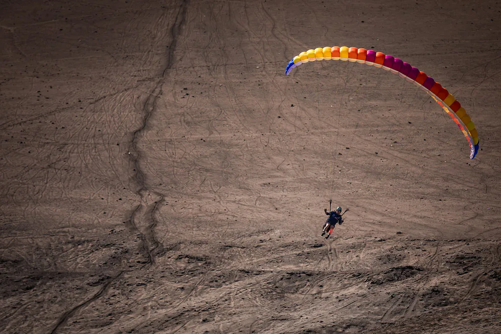 Un concorrente vola con un parapendio colorato sopra la sabbia di Playa La Lisera ad Arica, in Cile