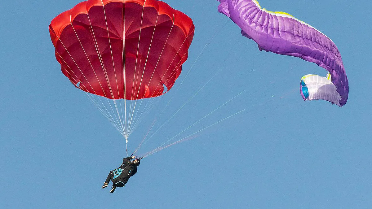 Un parachute de secours déployé à côté d’une aile de parapente déstabilisée