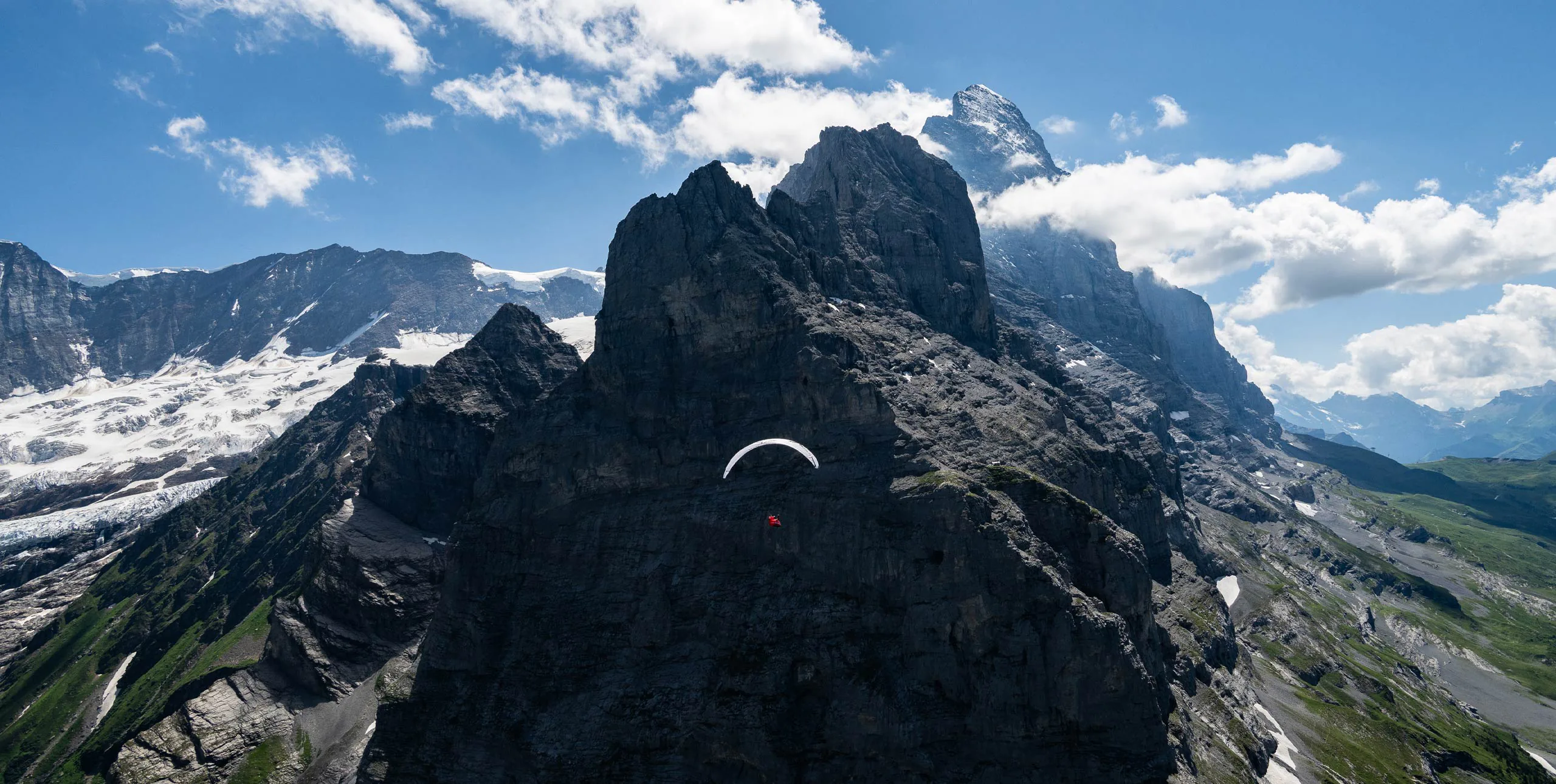 Ein Gleitschirm fliegt während der Eigertour 2026 vor einer hochalpinen Felswand